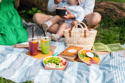 Close view of poke bowls on a blanket, family in the background - Starpik Stock