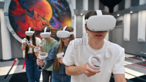 Group of four teens with VR headset and controllers playing games in a team. Tactfully walking through the VR arena. Slow motion - Starpik Stock