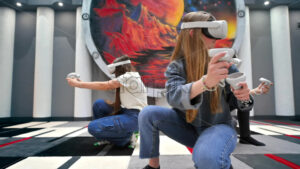 Group of three teens with VR headset and controllers playing games in a team on a VR arena, sitting and aiming. Slow motion - Starpik Stock