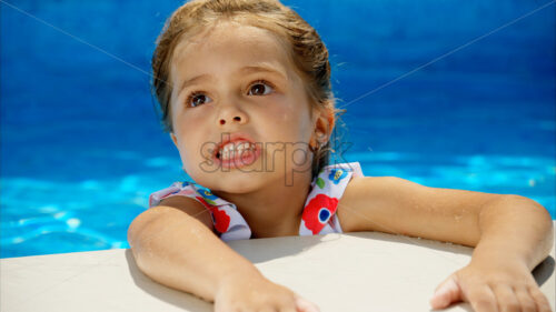 Little girl in sunglasses resting on white pool balloon - Starpik Stock