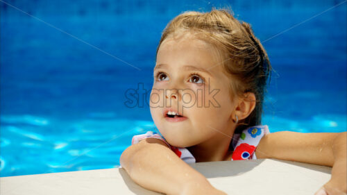 Little girl in sunglasses resting on white pool balloon - Starpik Stock