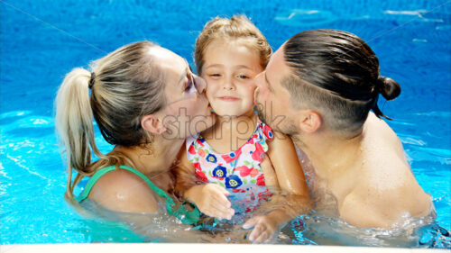 Mother with father and daughter resting and swimming in a pool in summer, happy family kissing - Starpik Stock