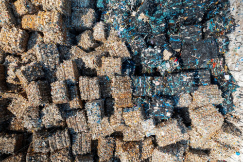 Multiple cubes of compressed plastic garbage near the waste recycling factory in open air. Vertical view - Starpik Stock