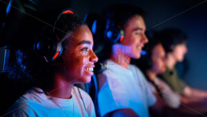 Premium stock photo – Multiracial group of teens in headsets playing video games in video game club with blue and red illumination. Keyboards and mice with illumination - Starpik