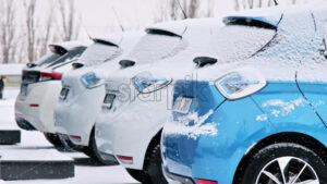 Row of parked electric cars covered with snow, winter - Starpik
