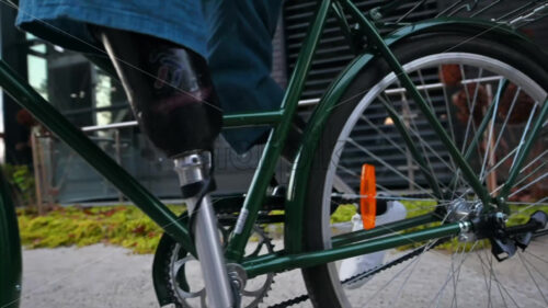 Slow motion view of a man with prosthetic legs. Getting on his bike and driving away - Starpik Stock