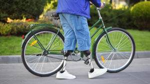 Slow motion view of a man with prosthetic legs. Putting the bike on the kickstand and standing next to it - Starpik Stock