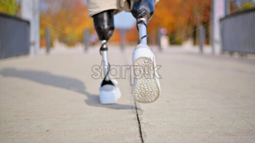 Slow motion view of a walking man with prosthetic legs and white sneakers - Starpik Stock