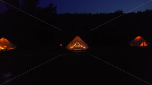 Tents with wooden chairs at glamping, lush forest around - Starpik