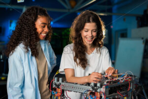 Two young women doing experiments in robotics in a laboratory. Robot on the table - Starpik Stock
