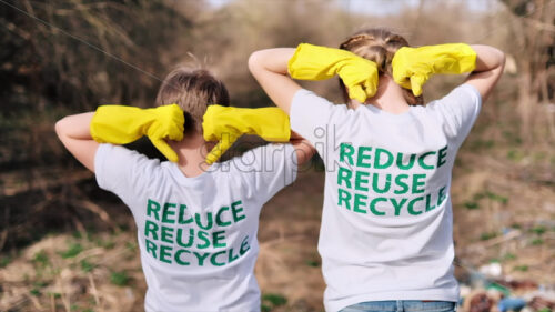 Video – Boy and girl in rubber gloves showing on the eco inscriptions on their T-shirts. Plastic garbage collection in a polluted clearing - Starpik Stock