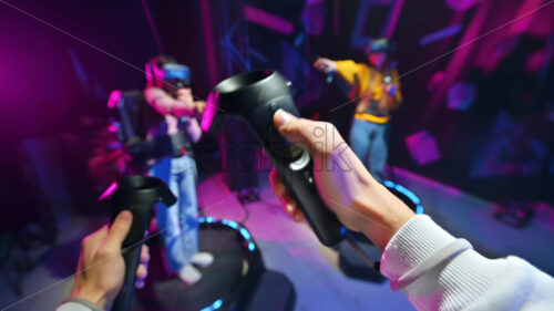 Video – Premium stock video footage – A group of joyful, interested young people playing on VR treadmill with helmets and controllers. POV, virtual reality - Starpik Stock