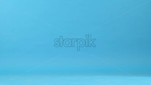 View of a man with prosthetic legs and white sneakers walking, blue background - Starpik Stock