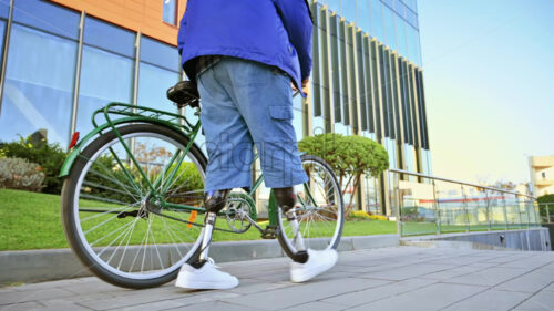 View of a man with prosthetic legs. Walking with a bicycle on the street - Starpik Stock