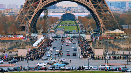 View of the cinematic Eiffel Tower in Paris from the Trocadero Square at sunset, France. Jena Bridge with multiple people and cars, Champ de Mars on the background - Starpik Stock