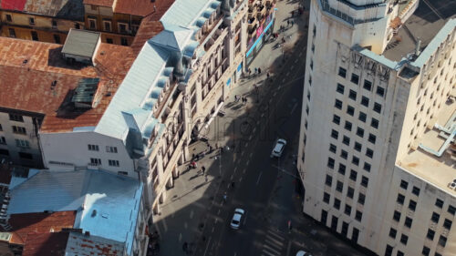 Aerial drone top view of a downtown road with moving traffic and walking people in sunlight. Bucharest, Romania - Starpik Stock