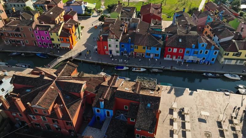 Video - Aerial drone view of boats on the sides of a canal near the colourful houses of Burano Island, Italy