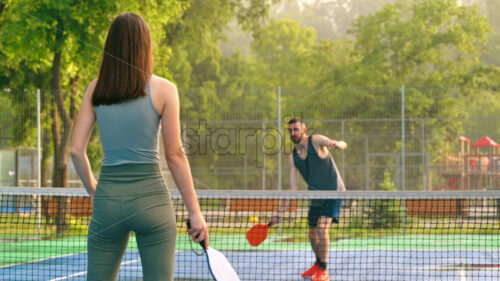 Video A man and a woman playing pickleball at sunrise, after rain - Starpik Stock