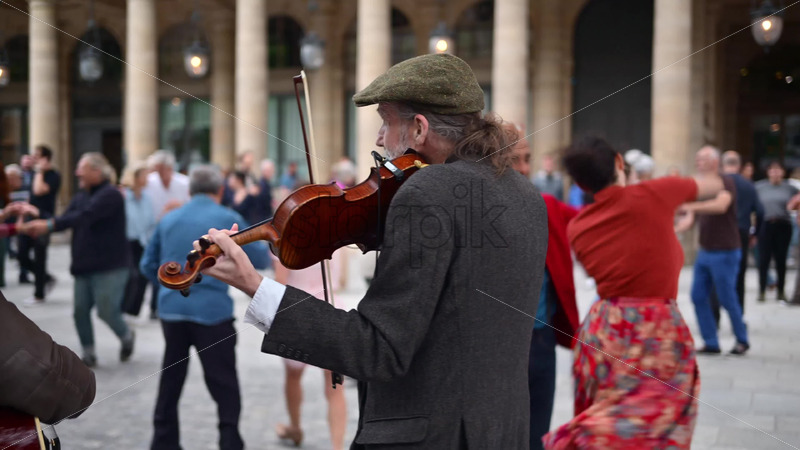 Video Paris, France – June 18, 2024: Men singing and playing instruments on the street with people dancing on the background - Starpik Stock