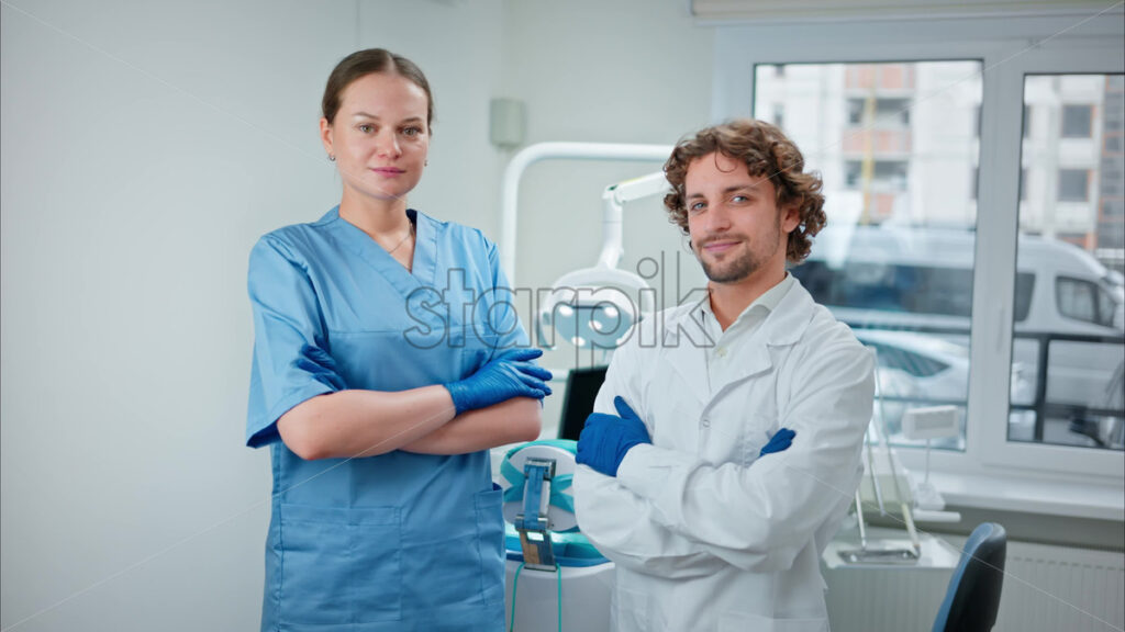Video Two dentists wearing scrubs and standing and smiling in a dental cabinet, in front of a window