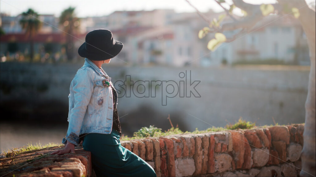 Tourist woman wearing black hat posing at the walls of Castle in Antibes, France - Starpik