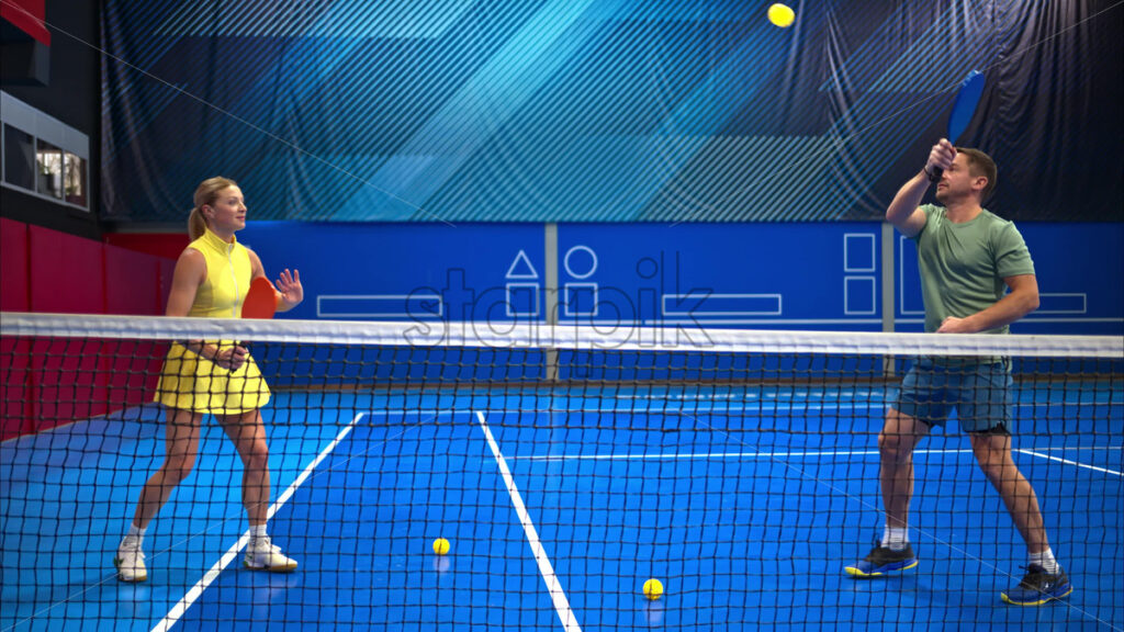 Video A man and a woman training to play pickleball on a blue, inside court - Starpik