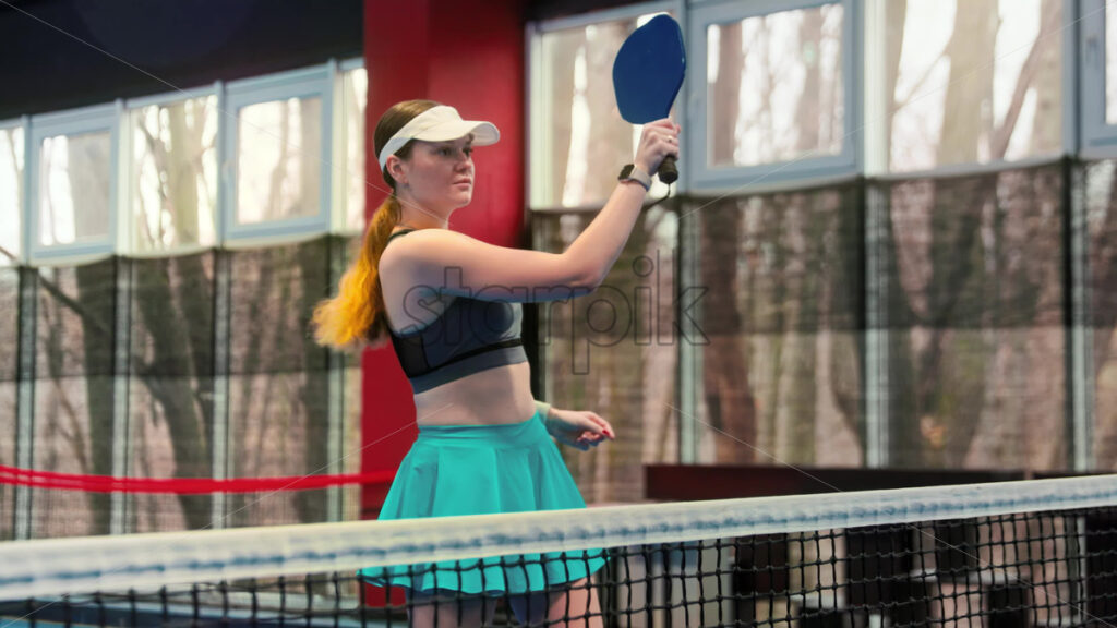 Video Woman playing pickleball on a blue, inside court - Starpik