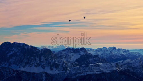 Aerial drone view hot air balloons flying over the Marmolada mountain in the Dolomites, northeastern Italy with the blue sky on the background - Starpik Stock