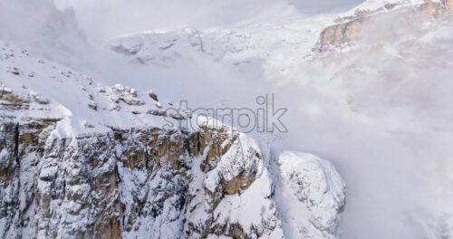 Aerial drone view of snow on the Sassongher mountain in the clouds, in the Dolomites, Italy - Starpik Stock