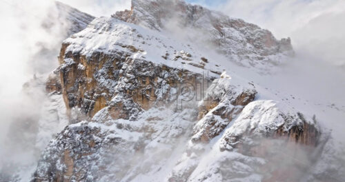Aerial drone view of snow on the Sassongher mountain in the clouds, in the Dolomites, Italy - Starpik Stock