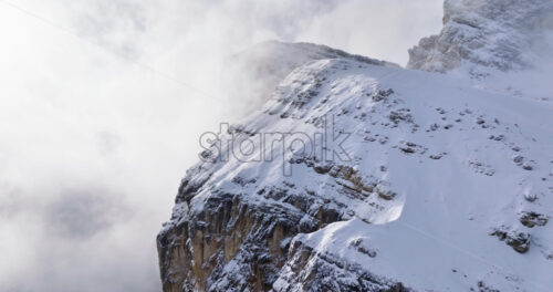 Aerial drone view of snow on the Sassongher mountain in the clouds, in the Dolomites, Italy - Starpik Stock