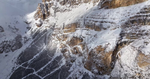 Aerial drone view of snow on the Sassongher mountain in the clouds, in the Dolomites, Italy - Starpik Stock