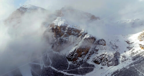Aerial drone view of snow on the Sassongher mountain in the clouds, in the Dolomites, Italy - Starpik Stock