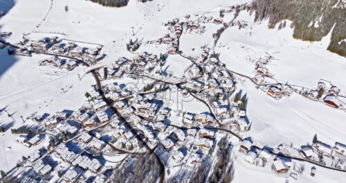 Aerial drone view of the Colfosco mountain village covered in snow, in South Tyrol, Dolomites, Northern Italy - Starpik Stock