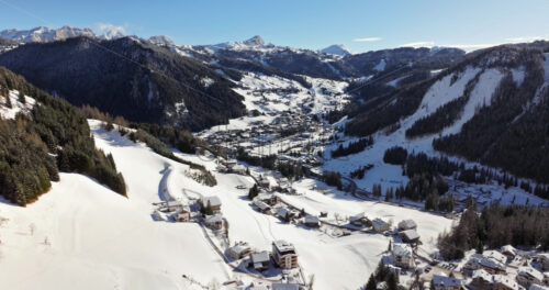 Aerial drone view of the Colfosco mountain village covered in snow, in South Tyrol, Dolomites, Northern Italy - Starpik Stock
