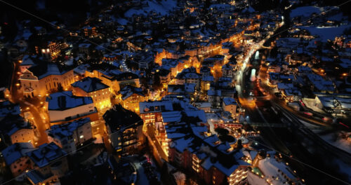 Aerial drone view of the Ortisei town covered in snow at night, within the Dolomites, in northern Italy - Starpik Stock