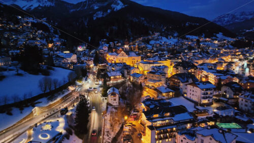 Aerial drone view of the Ortisei town covered in snow at night, within the Dolomites, in northern Italy - Starpik Stock