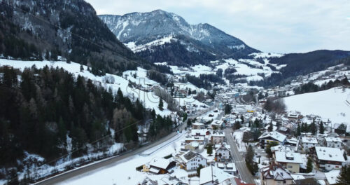 Aerial drone view of the Ortisei town covered in snow, within the Dolomites, in northern Italy - Starpik Stock
