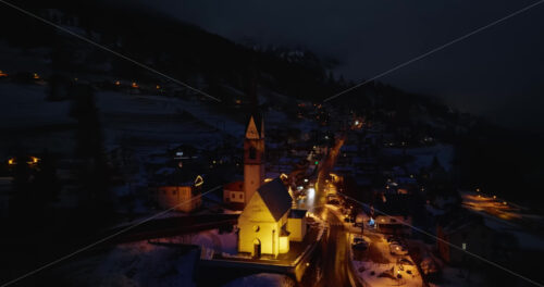 Aerial drone view of the San Lorenzo Church illuminated at night in the Selva di Cadore comune in Dolomites, Italy - Starpik Stock