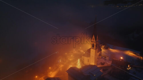 Aerial drone view of the San Lorenzo Church illuminated at night in the Selva di Cadore comune in Dolomites, Italy - Starpik Stock