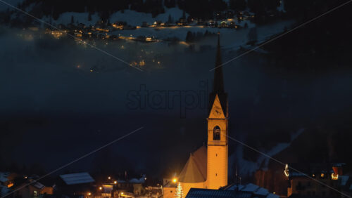Aerial drone view of the San Lorenzo Church illuminated at night in the Selva di Cadore comune in Dolomites, Italy - Starpik Stock