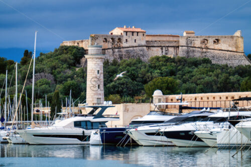 Antibes castle and port with boats and tower over blue sky - Starpik Stock