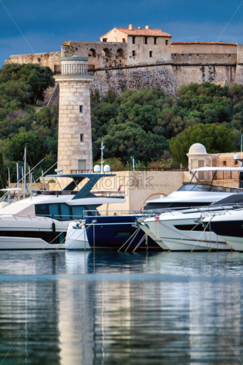 Antibes castle and port with boats and tower over blue sky - Starpik Stock