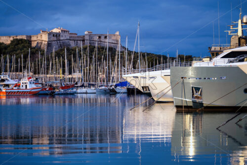 Antibes castle and port with boats and tower over blue sky - Starpik Stock