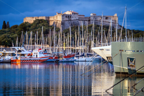 Antibes castle and port with boats and tower over blue sky - Starpik Stock