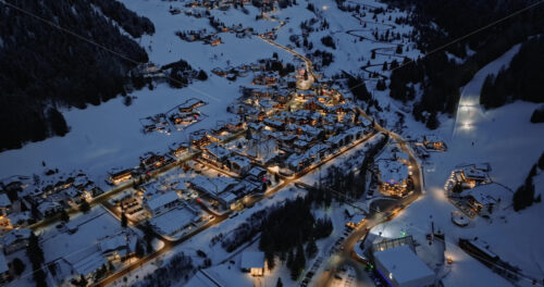 Corvara in Badia, Italy – January 9, 2025: Aerial drone view of the Corvara village covered in snow at night, in South Tyrol, Dolomites, in northern Italy - Starpik Stock