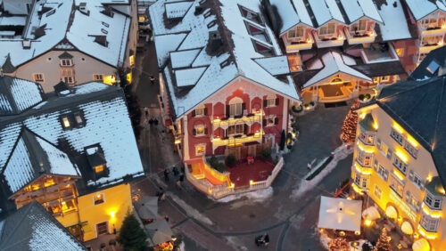 Ortisei, Italy – January 10, 2025: Aerial drone view of people walking through the Ortisei town covered in snow with Christmas decorations, within the Dolomites - Starpik Stock