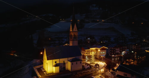 Selva di Cadore, January 9, 2025: Aerial drone view of the San Lorenzo Church illuminated at night in the Selva di Cadore comune in Dolomites, Italy - Starpik Stock