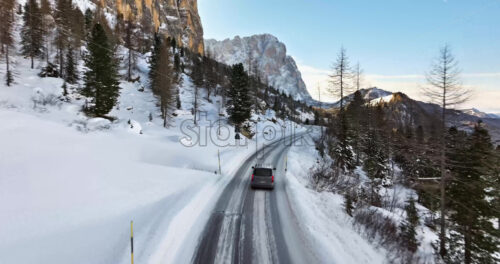 South Tyrol, Italy – January 12, 2025: Aerial drone view of a car moving through the Gardena Pass high mountain pass in the Dolomites - Starpik Stock