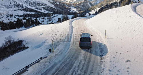 South Tyrol, Italy – January 12, 2025: Aerial drone view of a car moving through the Gardena Pass high mountain pass in the Dolomites - Starpik Stock